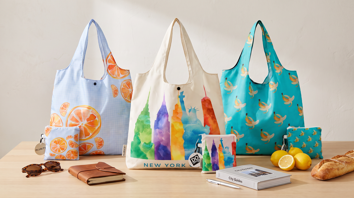 Colorful PLURiTy roll-up reusable tote designs displayed with coordinating storage pouches for gift selection.
